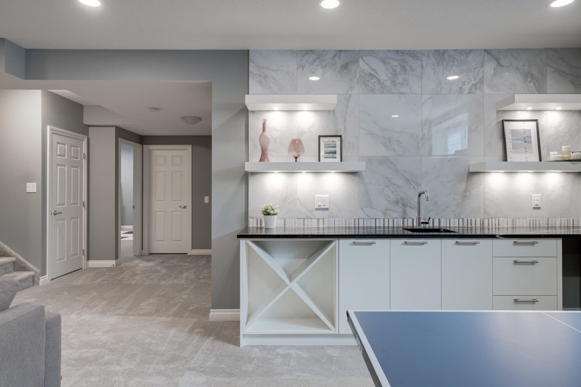 Basement bar with marble backsplash, lit shelves and ping pong table