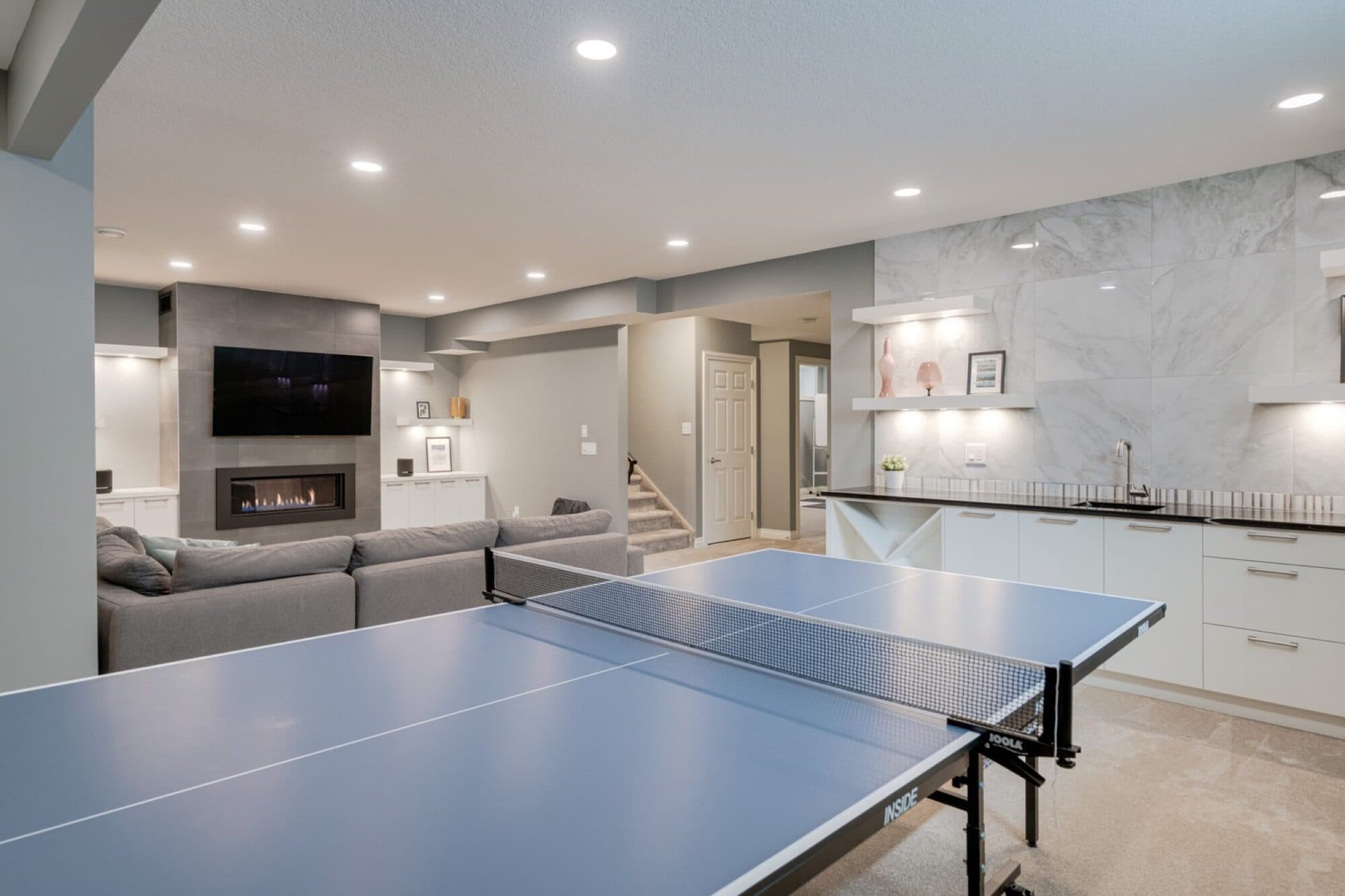 Basement rec room with ping pong, linear fireplace and bar