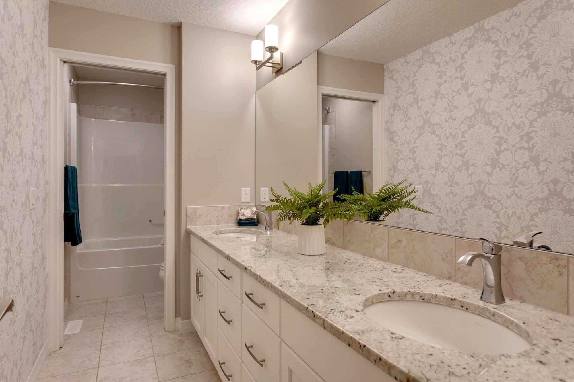 Basement bathroom with double granite vanity, damask wallpaper and tub-shower