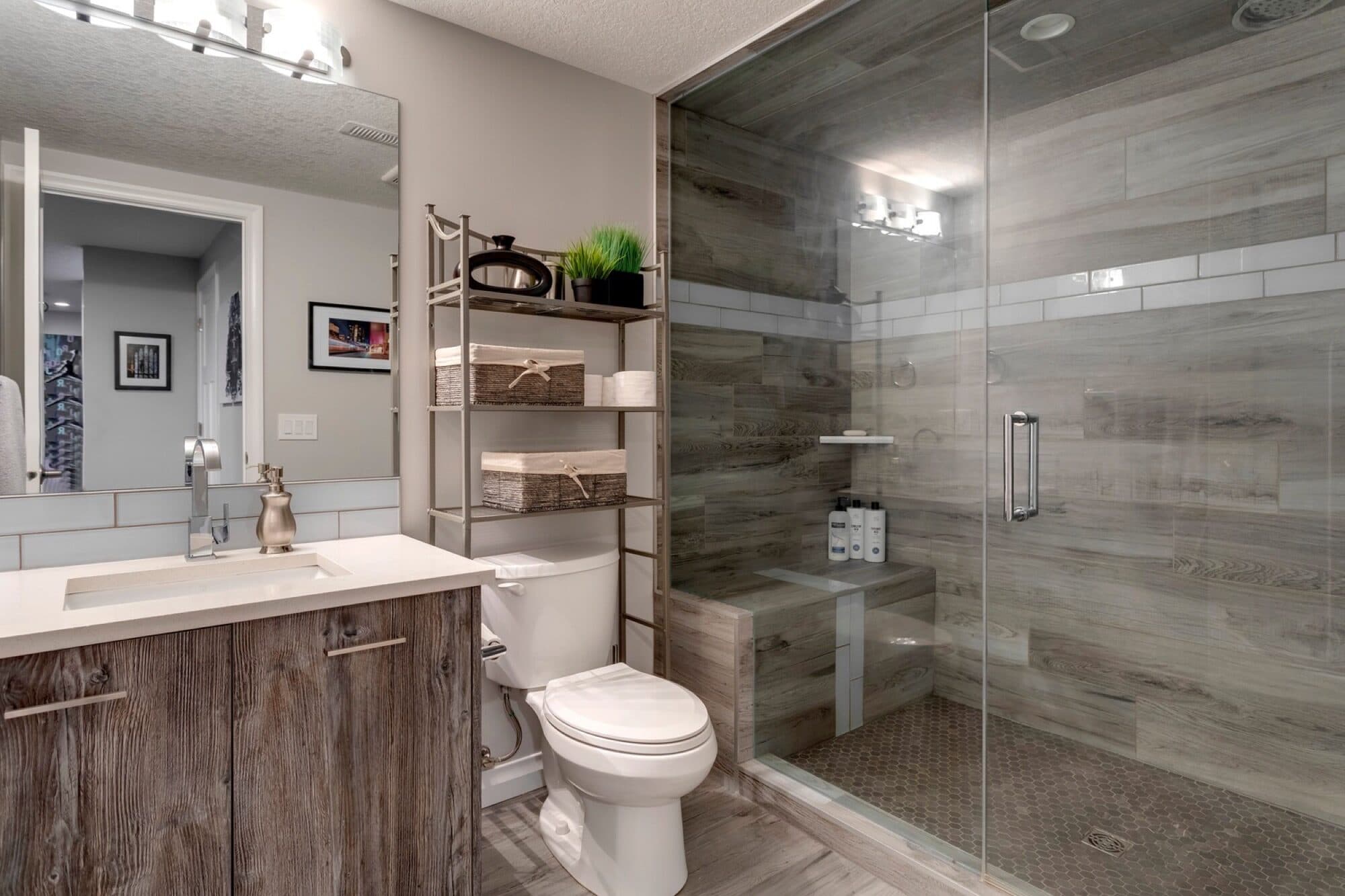 Basement bathroom with wood vanity, glass shower and grey tile