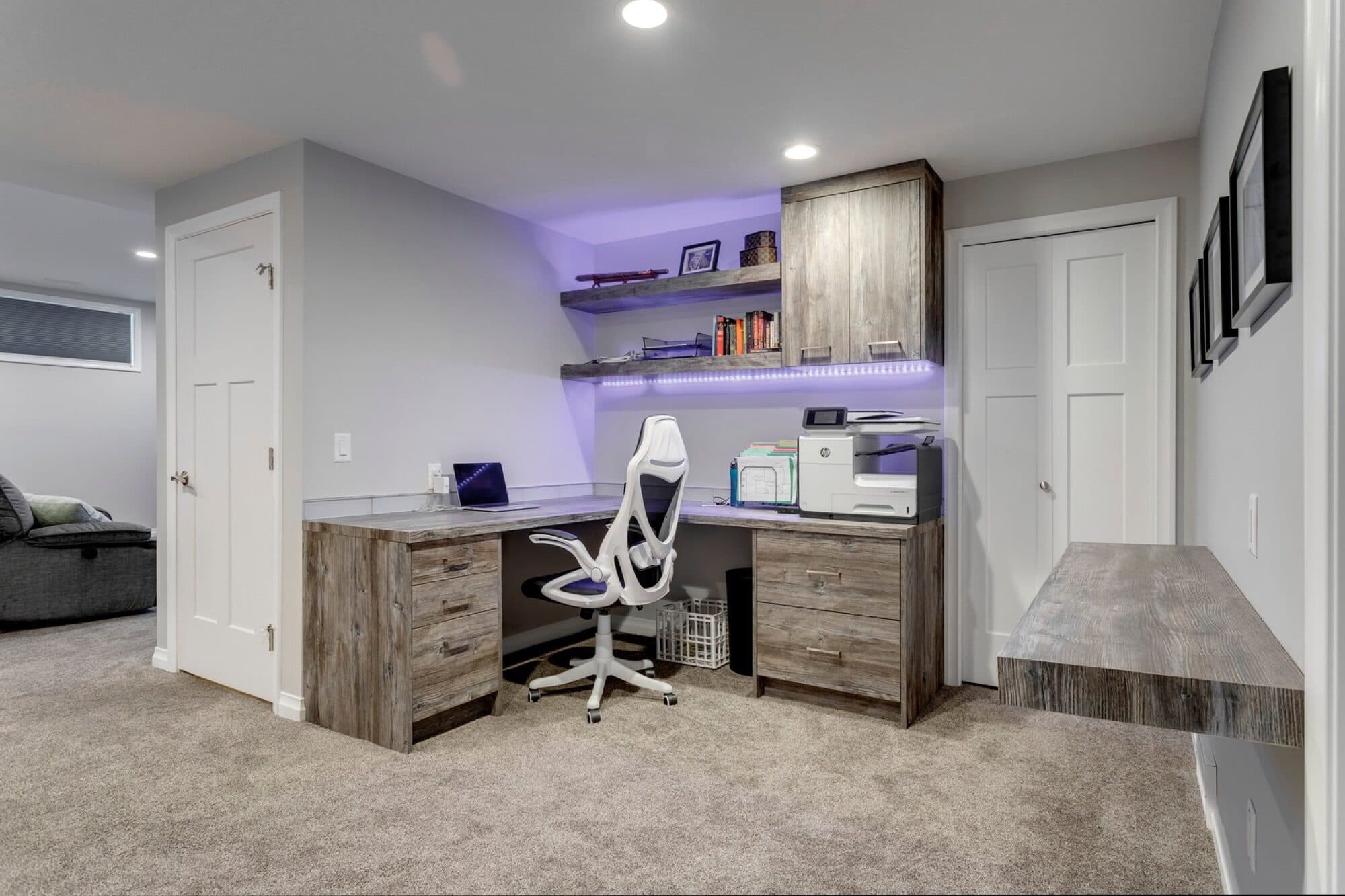 Basement built-in office with floating LED shelves and reclaimed wood desk