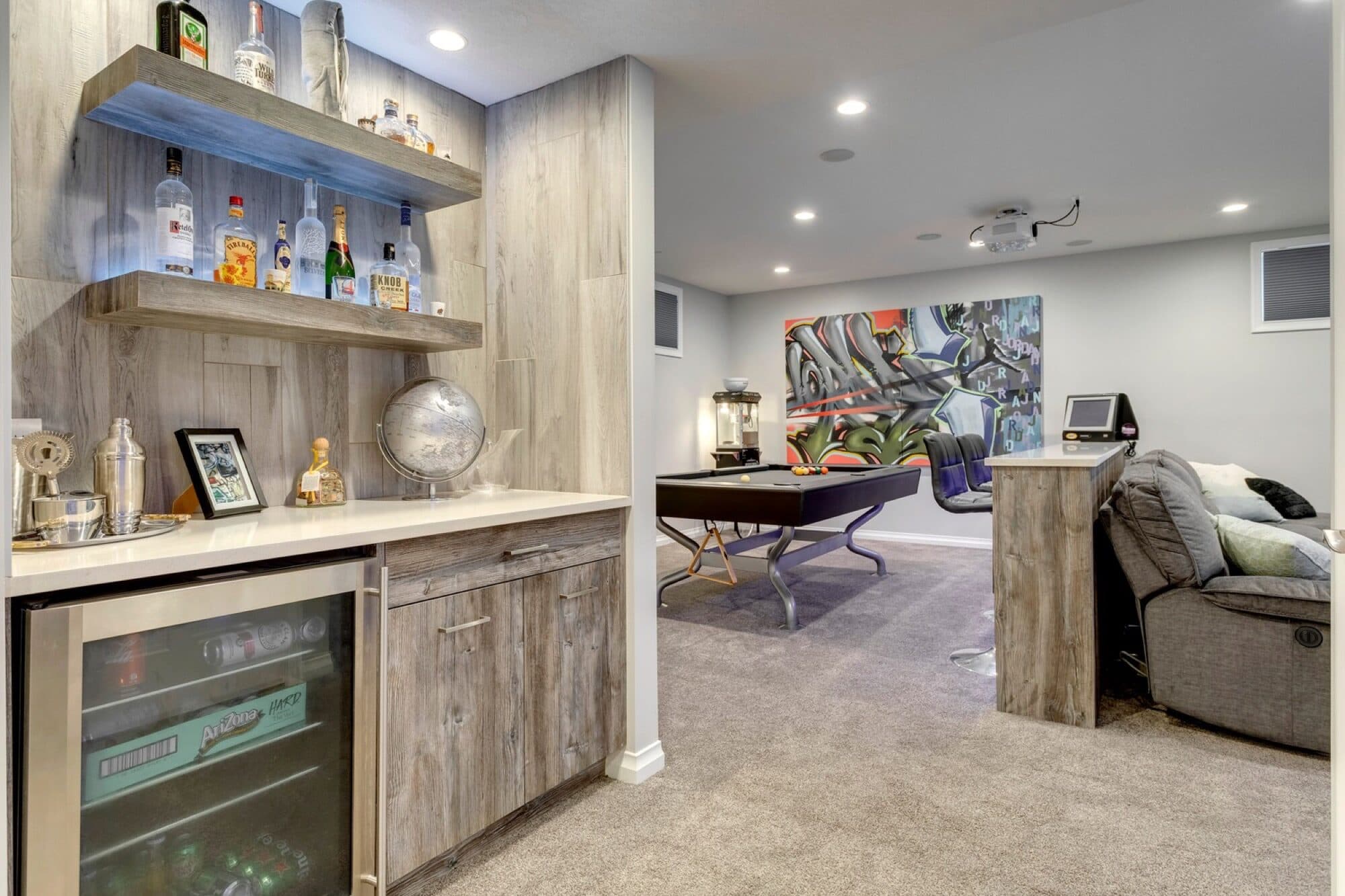 Basement wet bar with floating shelves, beverage fridge and pool-table lounge beyond
