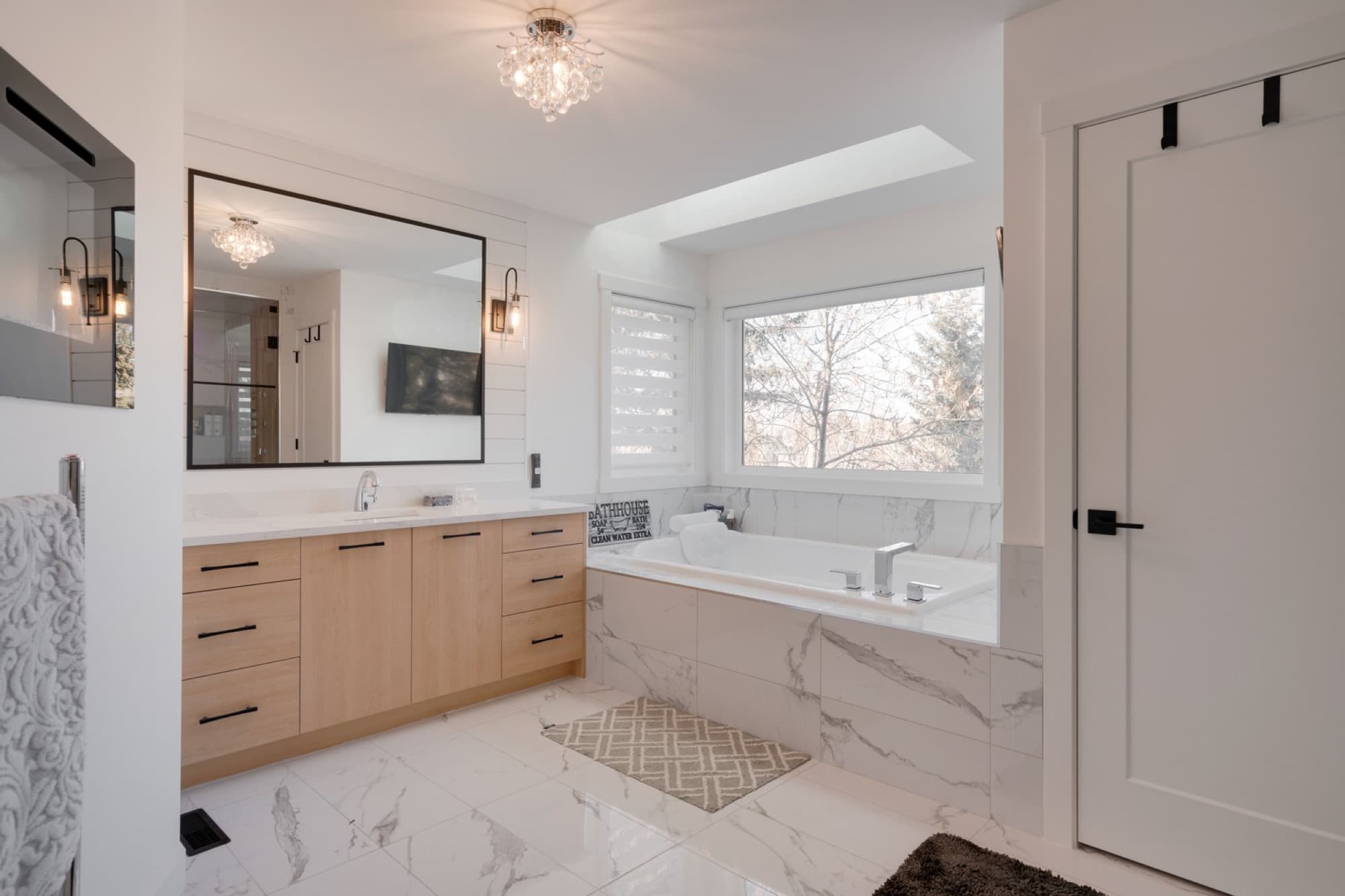 Ensuite with soaker tub, marble surround and natural wood vanity