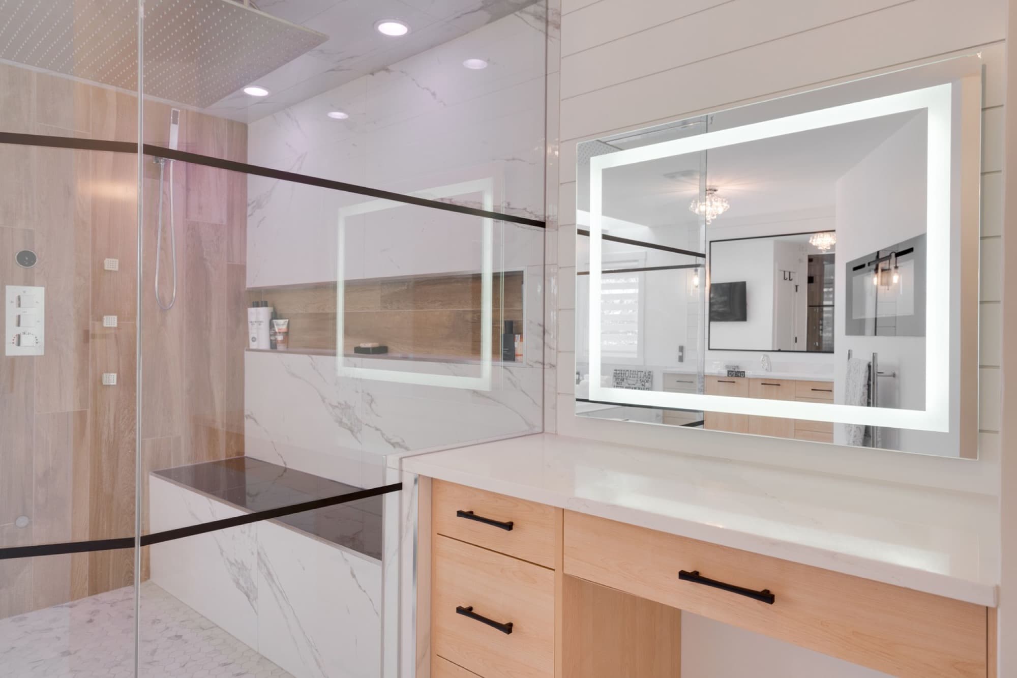 Ensuite vanity with LED lighted mirror and marble shower view