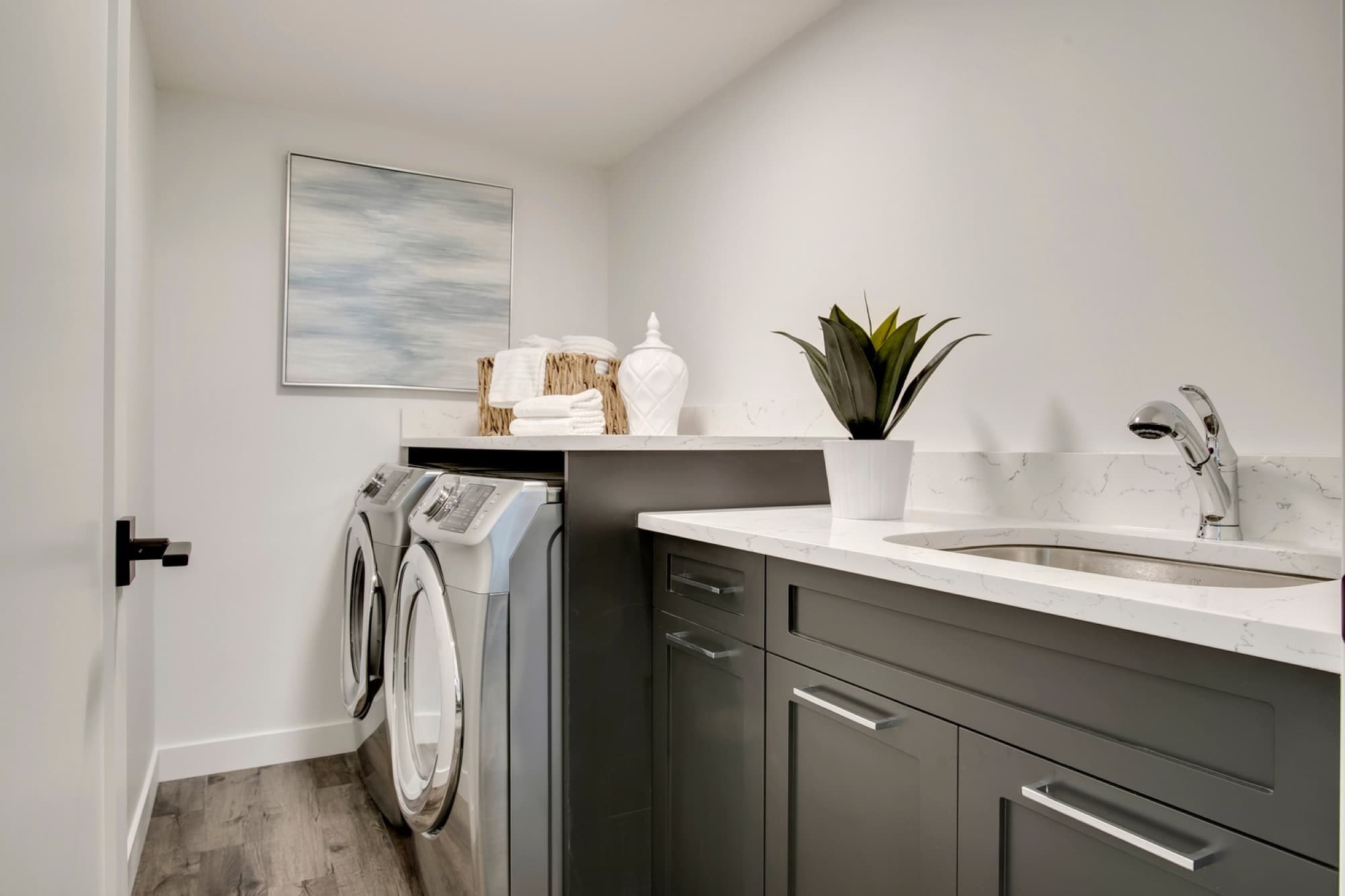 Finished laundry room with dark cabinets and marble countertop