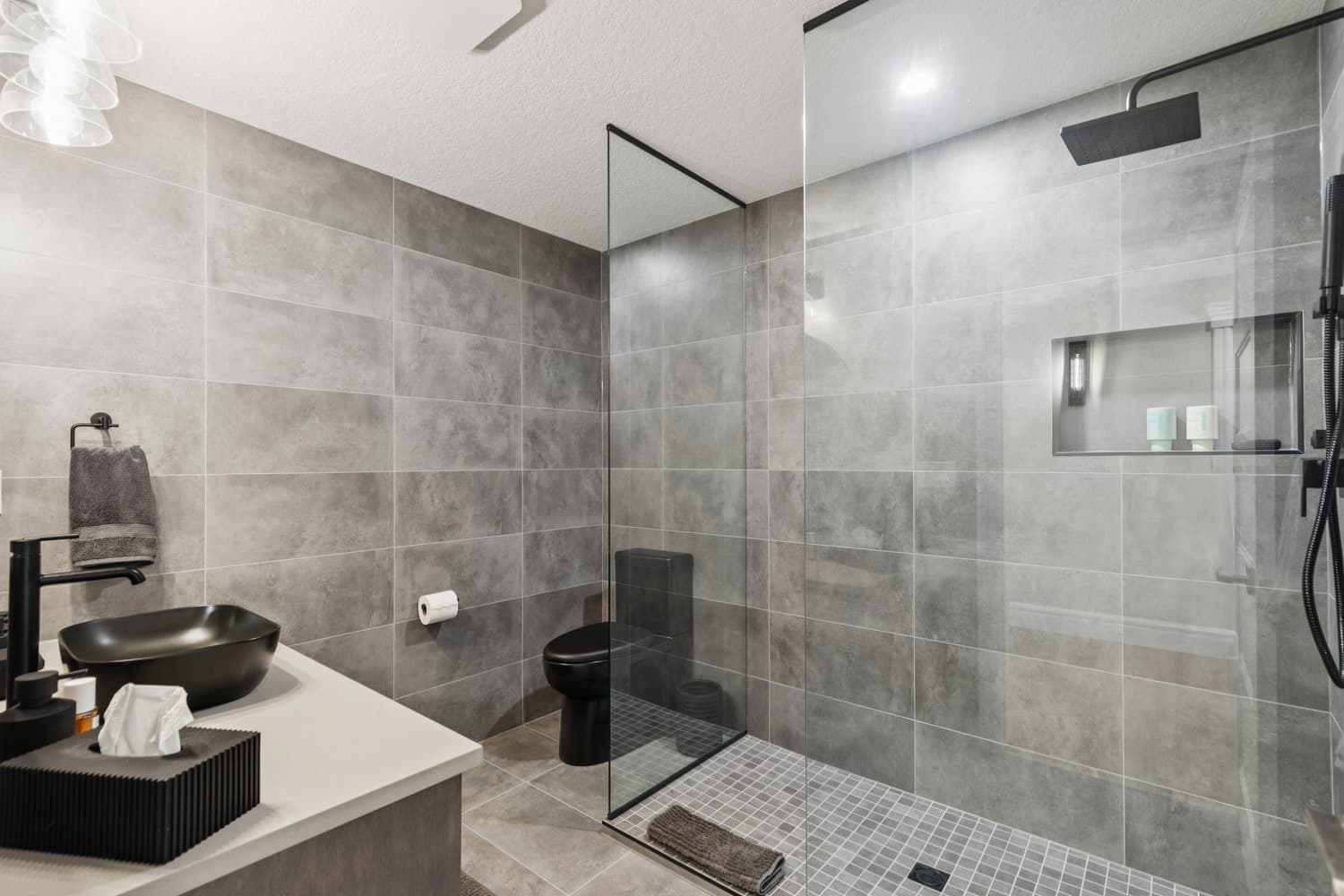 Modern basement bathroom with grey tile and black fixtures
