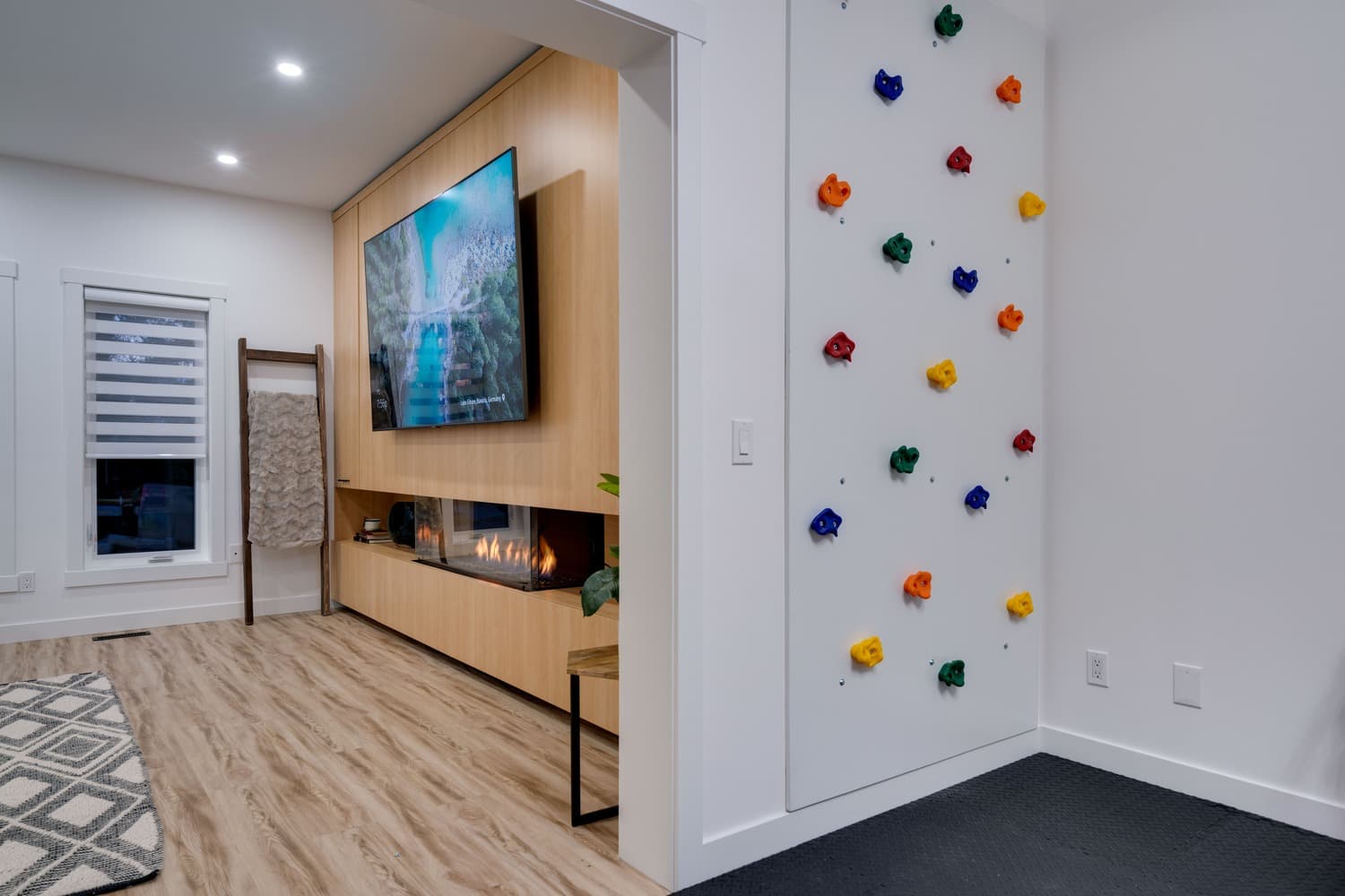 A finished Calgary basement by ReImagine Builders — wood feature wall, linear fireplace and a kids' climbing wall
