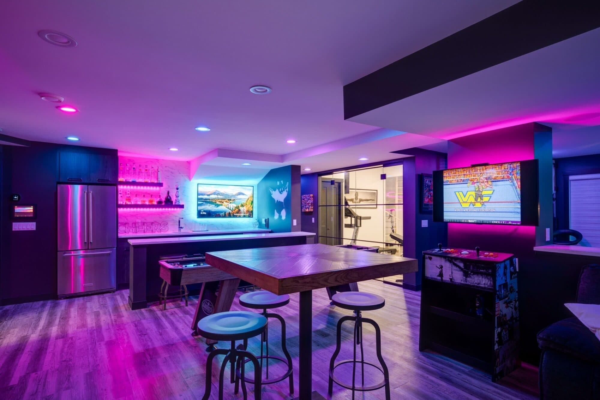 Basement entertainment bar with neon lighting, arcade machine and games area in Calgary