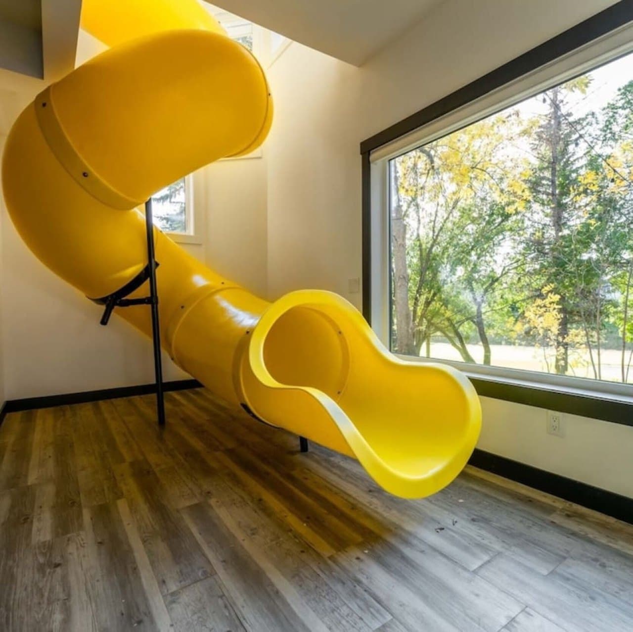 A custom yellow slide from the main floor landing into a finished Calgary basement by ReImagine Builders.